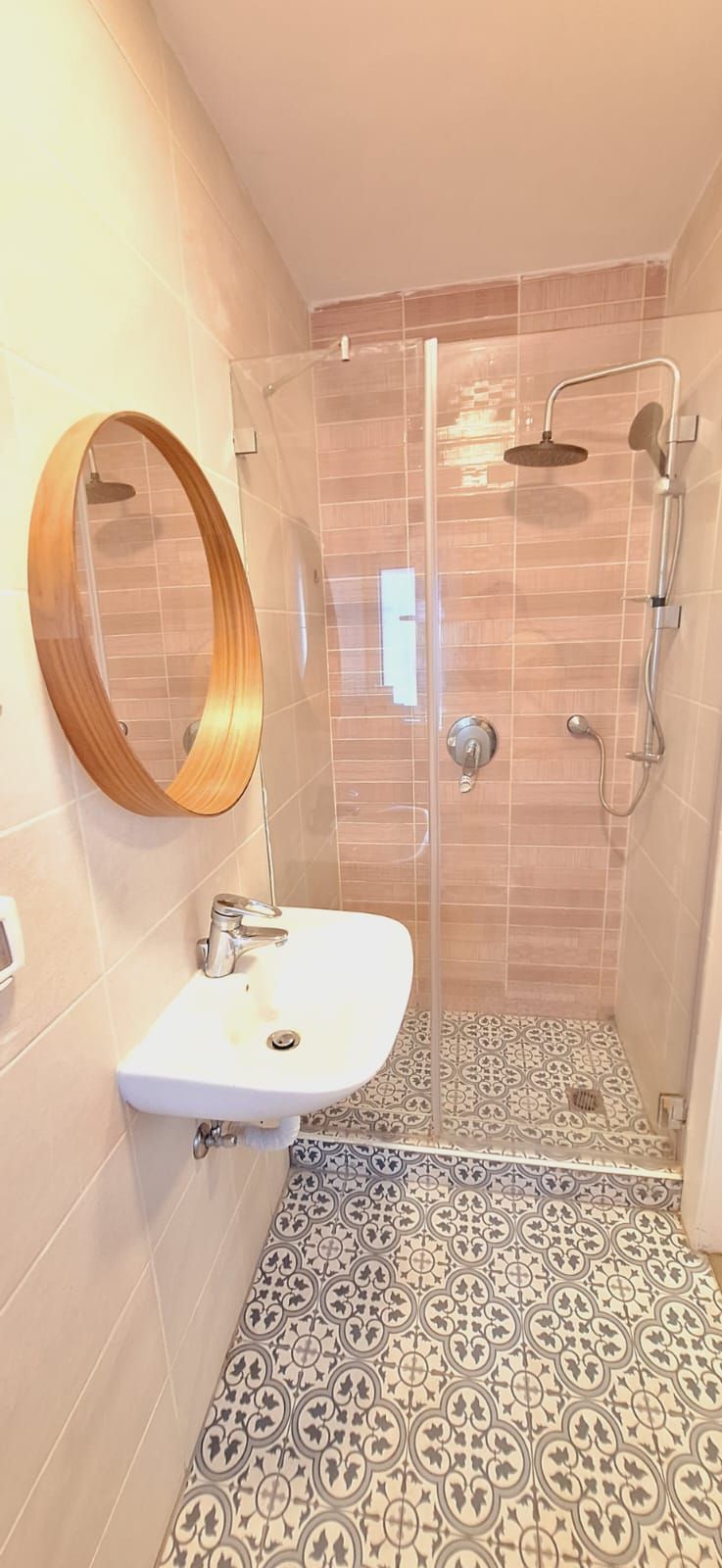 Un baño con ducha, lavabo y espejo.