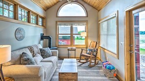 Una sala de estar acogedora con techo de madera, un sofá, un sillón mecedor y una mesa de centro.