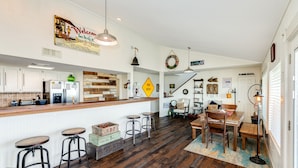 A spacious kitchen with wooden countertops, bar stools, and a dining area with a wooden table and chairs.