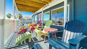 A covered outdoor area with colorful Adirondack chairs and a wooden deck.