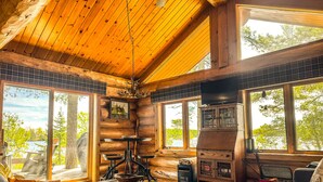 A log cabin interior with a fireplace, large windows, and a cozy seating area. - Beautiful Private Island Getaway-Boat Rental Available! (Tower)