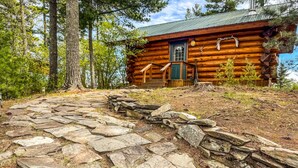 A log cabin with a stone pathway leading to it, surrounded by trees. - Beautiful Private Island Getaway-Boat Rental Available! (Tower)