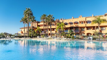 Un hotel con piscina, palmeras y sillas de descanso.