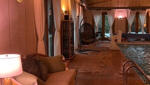 A wooden interior with a sofa, a hanging chair, and a pool area. - INDOOR POOL, HOT TUB, PRIVATE 86 acre Retreat and Event Space (Hanover)