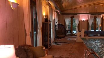 Un intérieur en bois avec un canapé, un fauteuil suspendu et un espace piscine.
