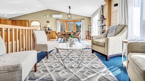A spacious living room with a high ceiling, a dining area with wooden furniture, and a view of the outdoors through large windows. - INDOOR POOL, HOT TUB, PRIVATE 86 acre Retreat and Event Space (Hanover)