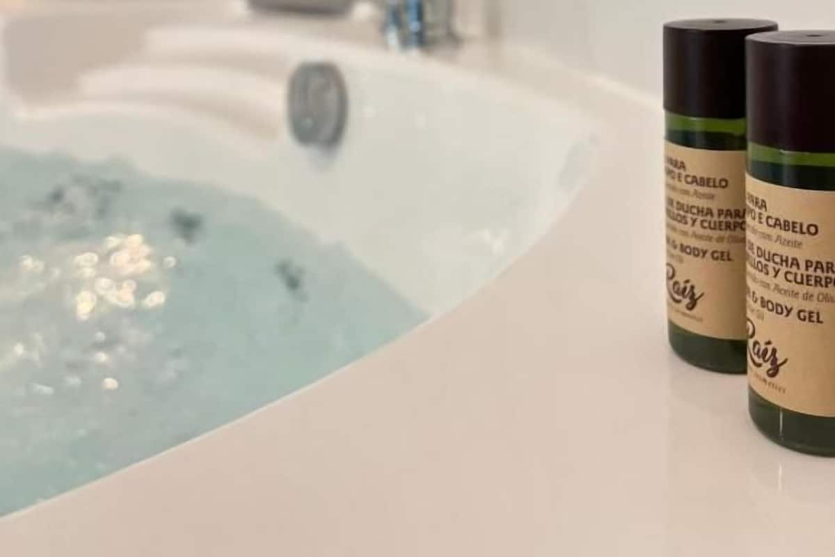 Un baño con una bañera y dos botellas de gel de baño en el mostrador.