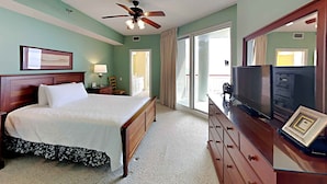 A hotel room with a bed, a dresser, a television, and a ceiling fan.