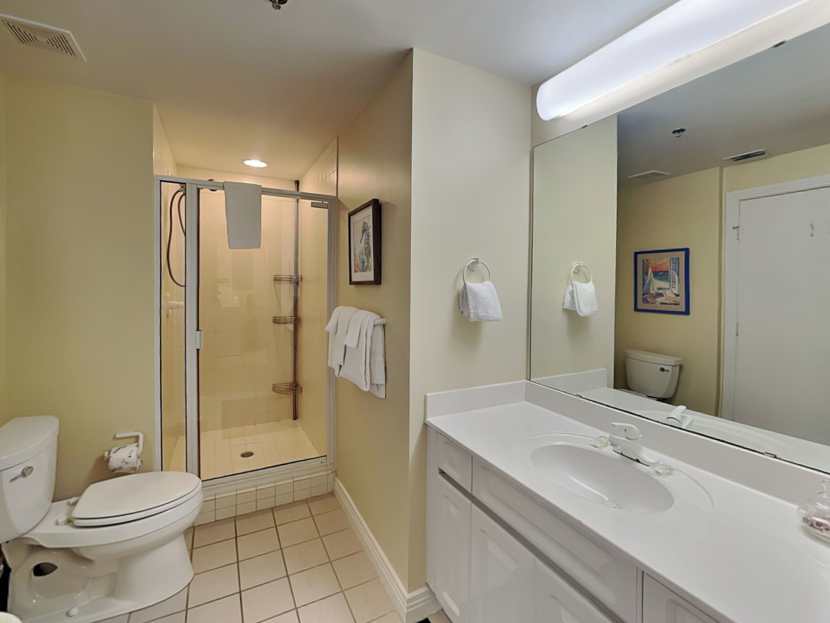 A bathroom with a toilet, a shower, a sink, and a large mirror.