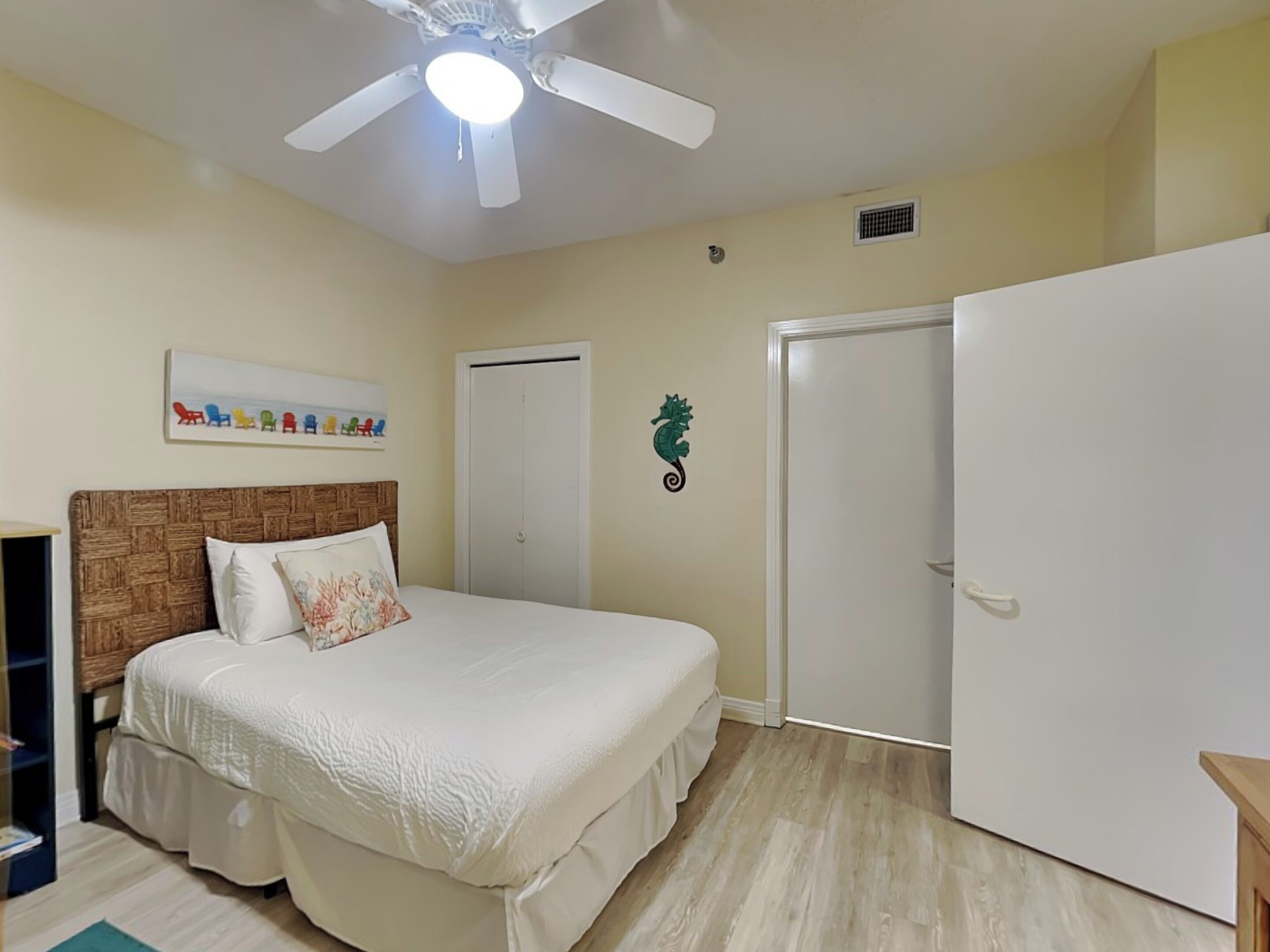A bedroom with a bed, a ceiling fan, a wardrobe, and a door.