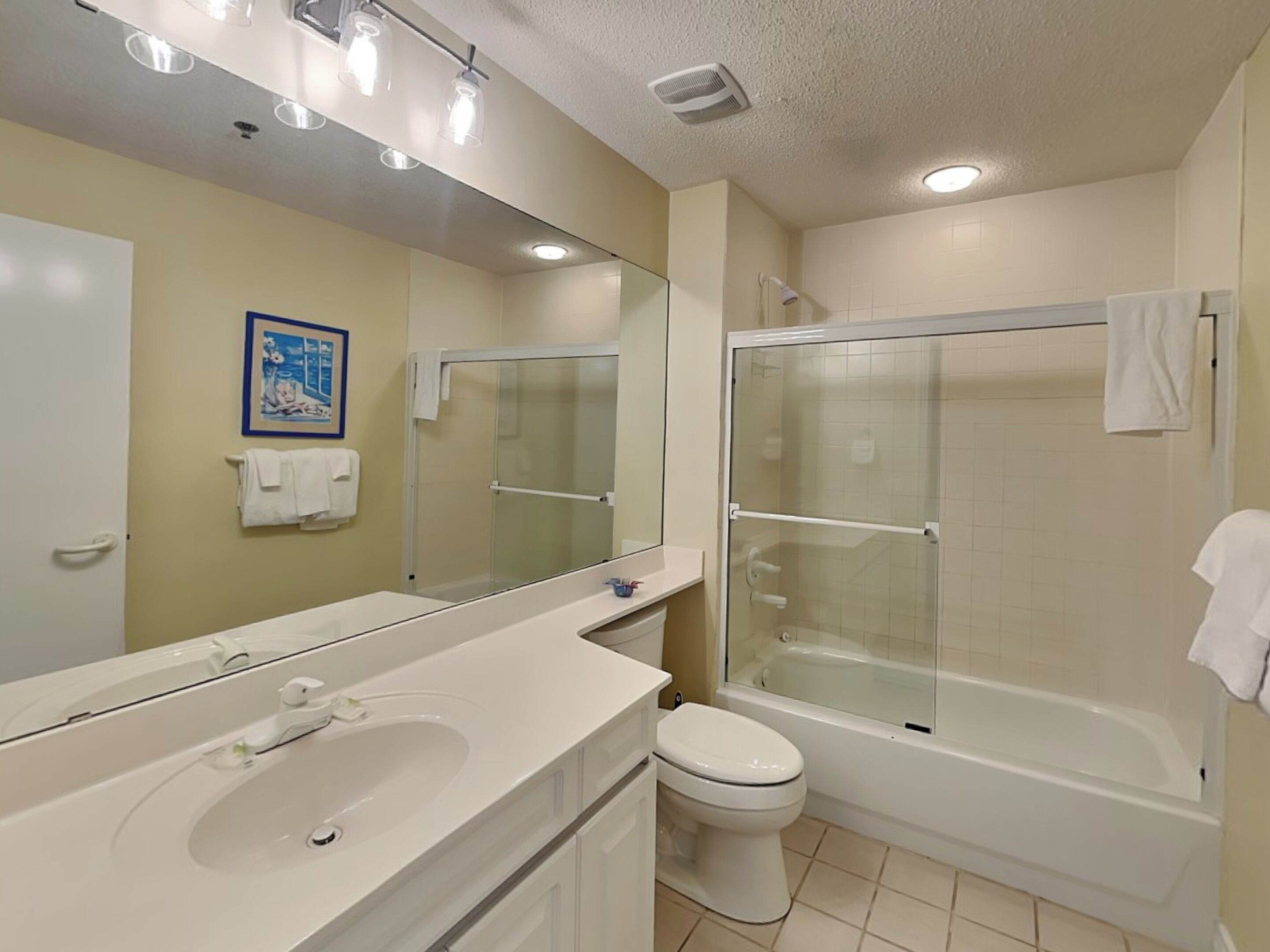 Une salle de bain équipée d’un lavabo, de toilettes, d’une douche et d’un grand miroir.