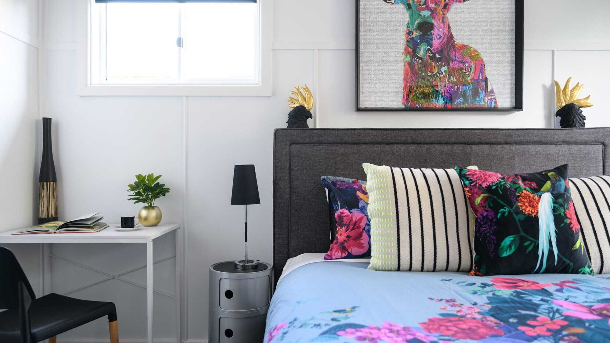 A bedroom with a bed, a desk, a chair, a lamp, and a window.
