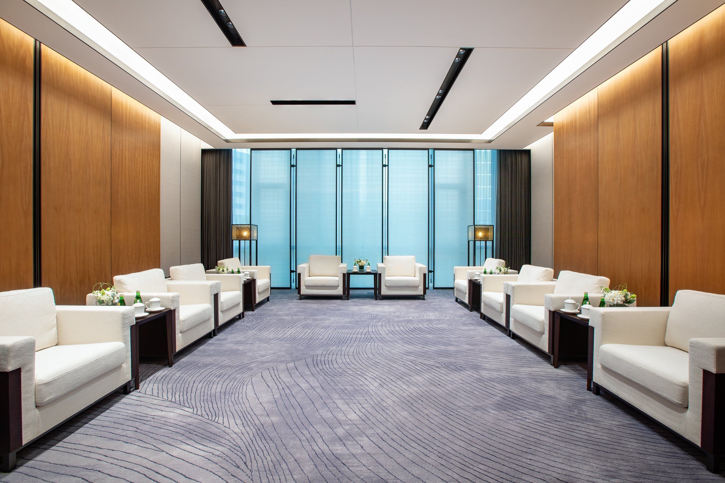 A conference room with a long table, four white sofas, and a carpeted floor.