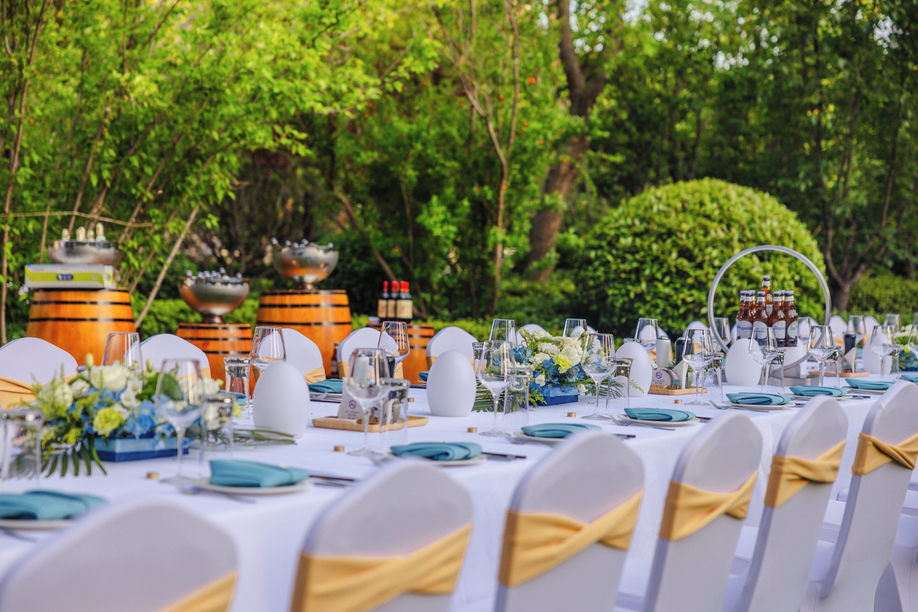 A banquet table set for a formal event with white tablecloths, neatly arranged plates, glasses, and cutlery.
