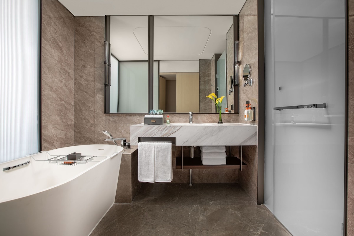Une salle de bain moderne avec une grande baignoire, un lavabo avec un miroir et une douche.