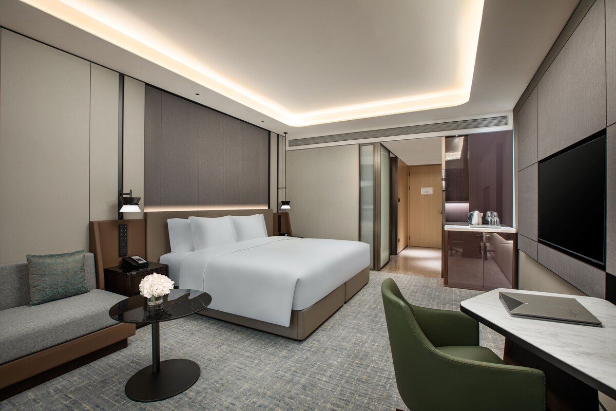 Une chambre d’hôtel moderne équipée d’un grand lit, d’un bureau, d’un canapé et d’une télévision.