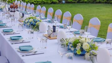 A long dining table set with white and blue tableware, glassware, and floral centerpieces.