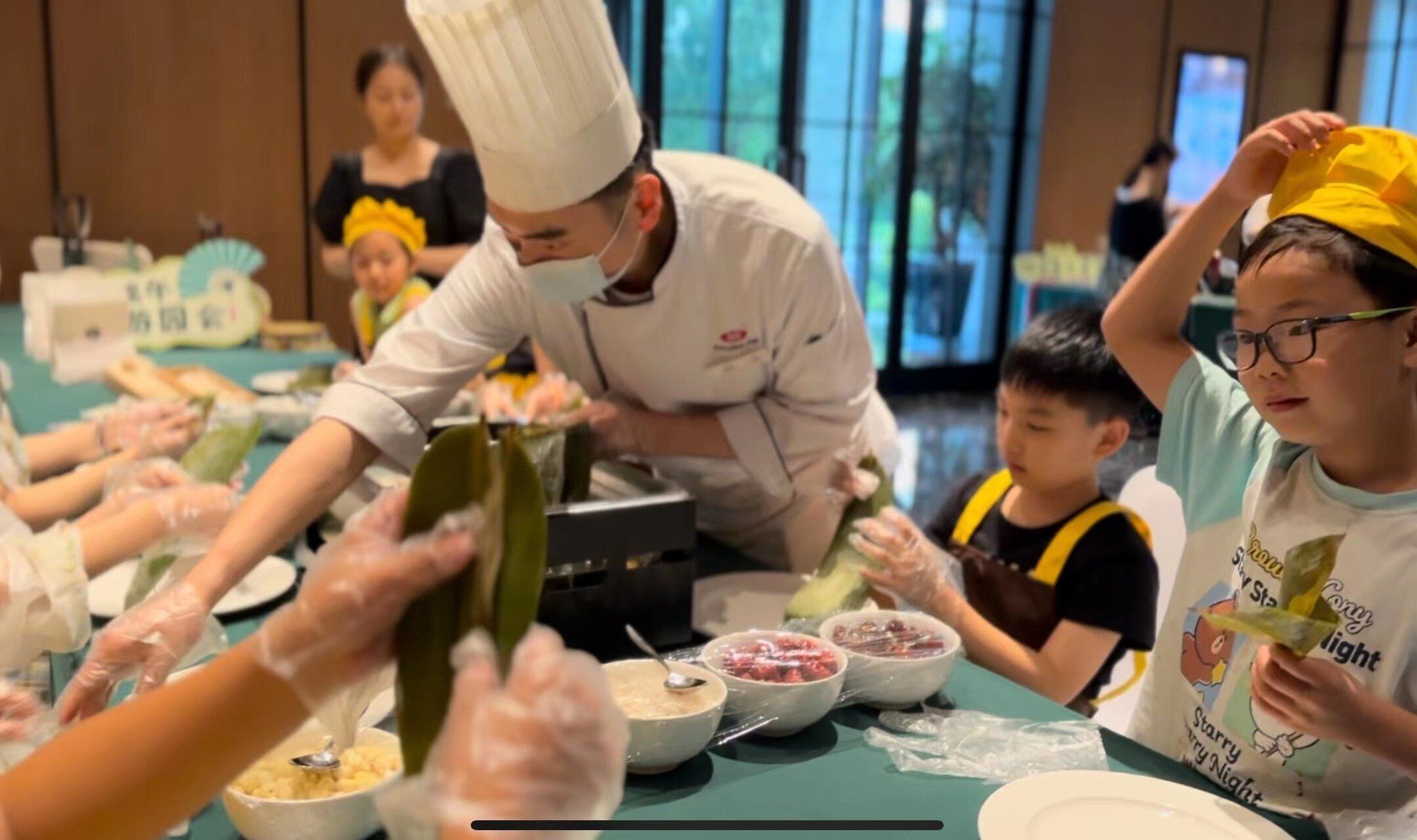 A group of people engaged in a cooking activity, with a chef instructing them.