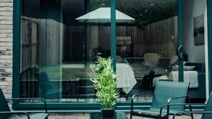 A modern building with large glass doors, a small window, and a potted plant in the foreground. - Hayy Collection Townhouse Living at Cliff Oaks (Leeds)