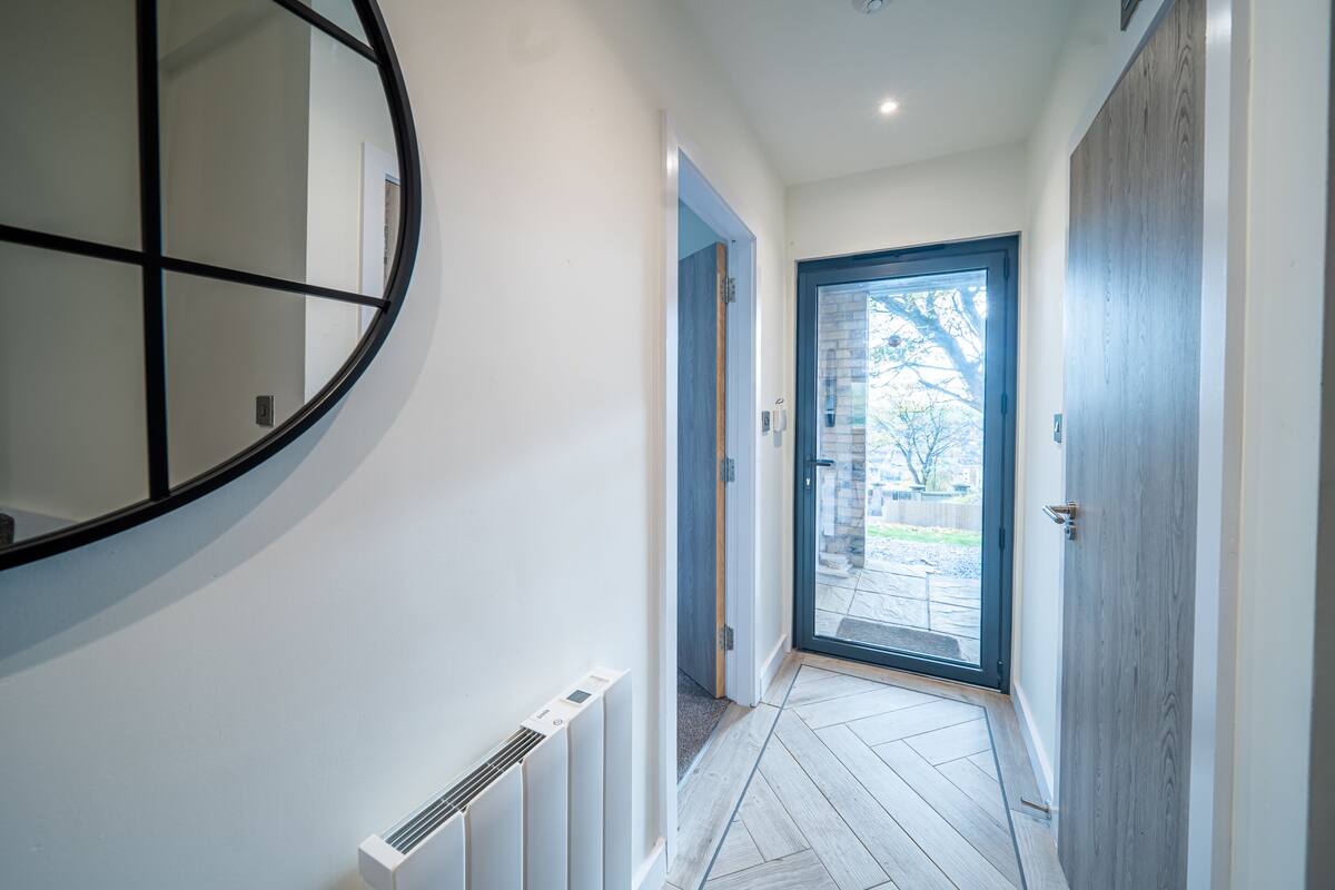 A hallway with a round mirror, a radiator, and a door leading to an outdoor area.