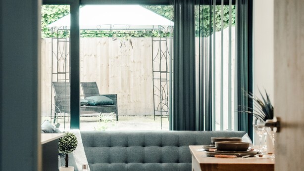 A modern living room with a grey sofa, wooden coffee table, and a dining table. - Hayy Collection Townhouse Living at Cliff Oaks (Leeds)