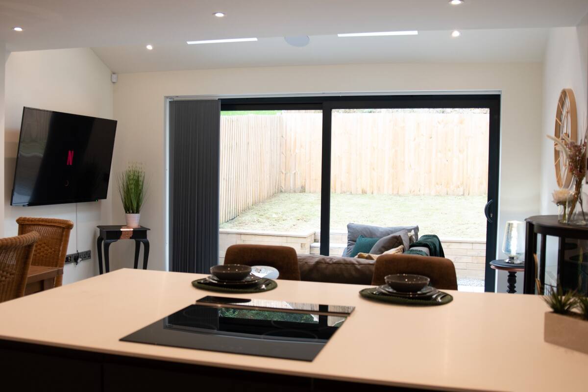 A modern dining area with a large table, chairs, and a television mounted on the wall.
