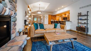 Un salon chaleureux avec une cheminée en pierre, un canapé en cuir et une table basse en bois.