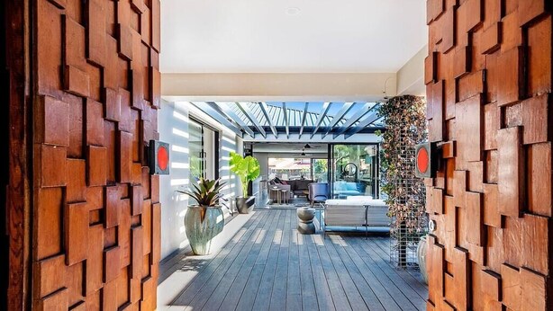 A modern interior with a wooden floor, a seating area with a sofa and chairs, and a large potted plant. - Capri Waterfront Oasis Pool, 4bd steps to Surfers (Gold Coast)