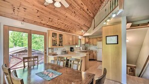A spacious kitchen with wooden cabinets, a large island, and a dining area with a wooden table and chairs. - Waterfront Cabin on Long Lake w/ Dock & Kayaks! (Comstock)