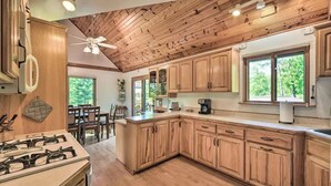 A kitchen with wooden cabinets, a gas stove, and a ceiling fan. - Waterfront Cabin on Long Lake w/ Dock & Kayaks! (Comstock)