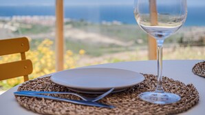 Uma mesa posta com uma taça de vinho, pratos e talheres, com vista para uma paisagem deslumbrante.