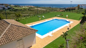 Piscina com vista para o mar, rodeada por uma área gramada e um edifício com a inscrição 'Depurador'.