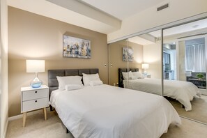 Relax in a serene space with a large bed, bedside table, and full-length mirror.
