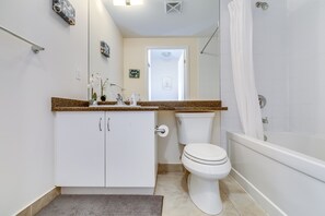 Bathroom features a white toilet, bathtub, and granite countertop.