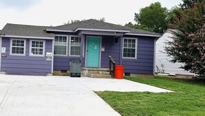 A single-story house with a purple exterior, a green door, and a small front porch.