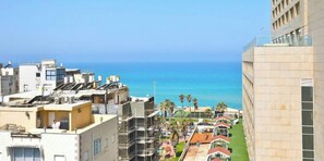 Un paysage urbain côtier avec vue sur la mer, des bâtiments modernes et un ciel dégagé.