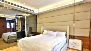 A modern hotel room with a large bed, a bedside table, and a mirror. - O&O Group - Deluxe Beachfront 3 BR Penthouse (Bat Yam)