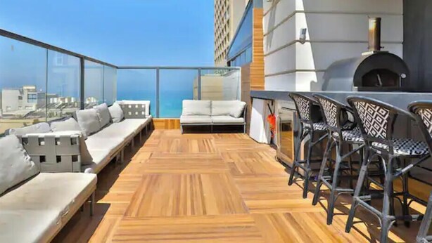 A rooftop terrace with wooden flooring, seating areas, and a pizza oven. - O&O Group - Deluxe Beachfront 3 BR Penthouse (Bat Yam)