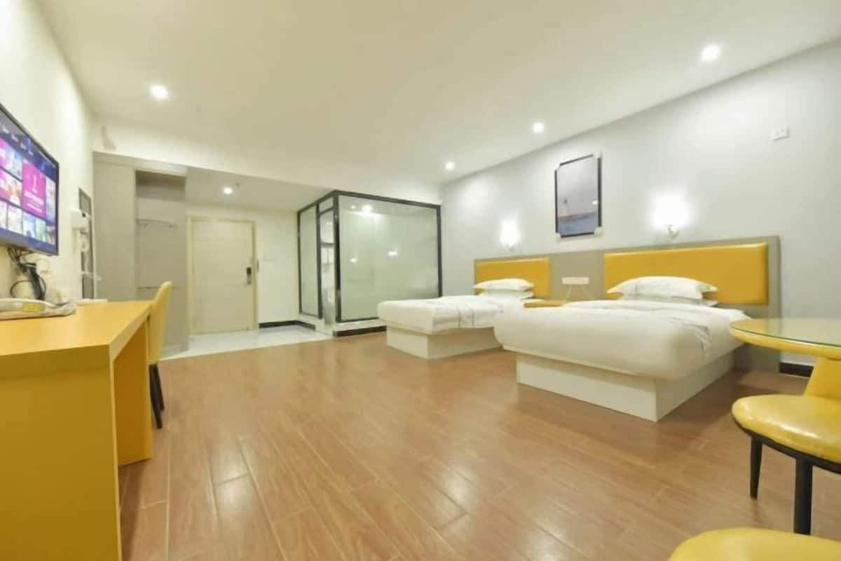 A modern hotel room with a bed, a desk, and a glass partition.