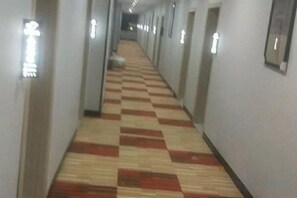 A long hallway with a checkered carpet and light fixtures on the walls. - Qinji Hotel (Wuyue Plaza Baishihu Park) (Qinzhou)