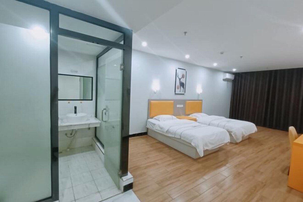Camera d'albergo con cabina doccia in vetro, letto con biancheria bianca, comodino e condizionatore a parete.