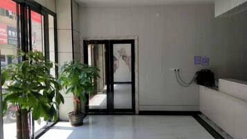 A hallway with a potted plant, a door, and a wall-mounted telephone.