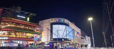 A modern building with a prominent signage, a public square with a fountain, and a well-lit street.