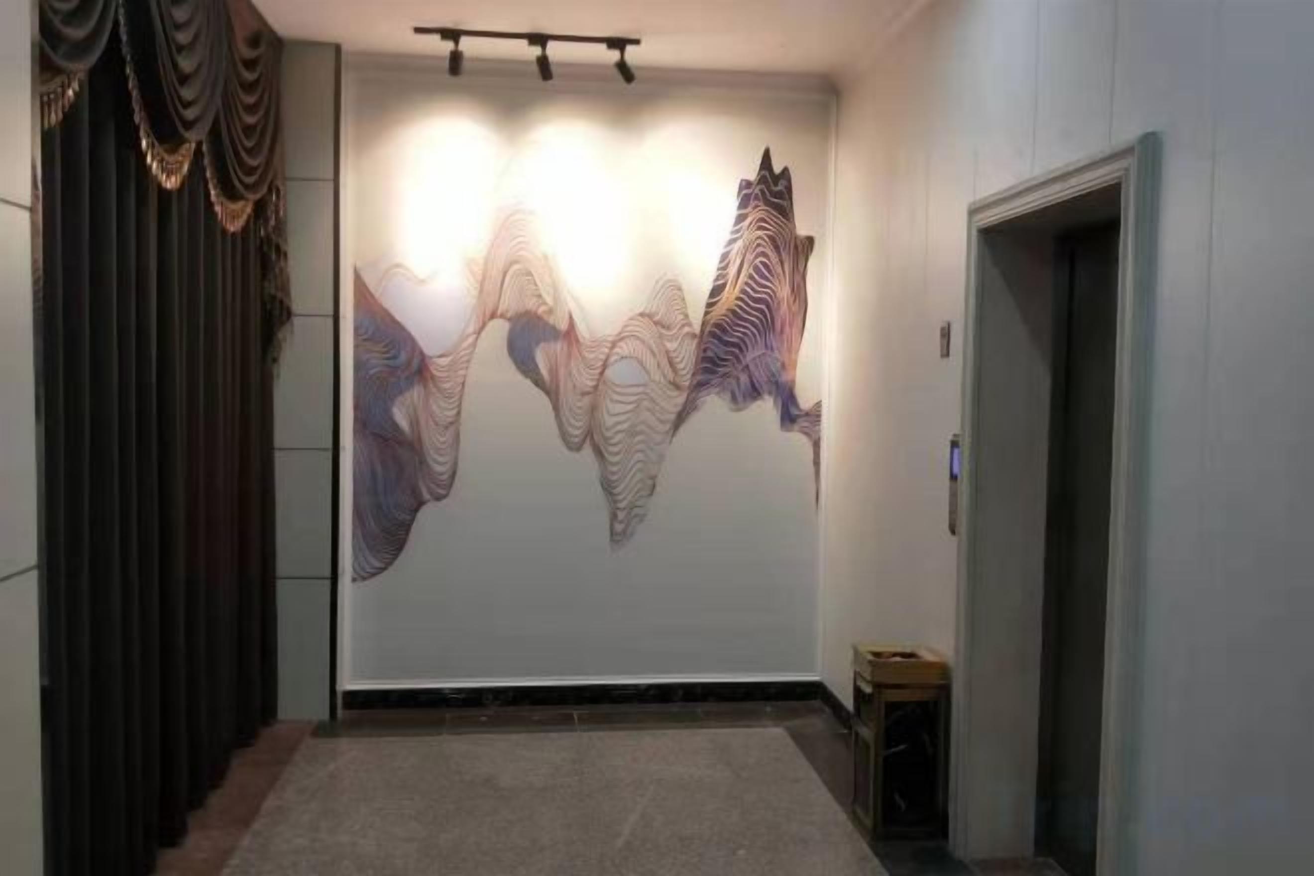 A hallway with a large abstract wall art, a door on the right, and a small table with a chair.