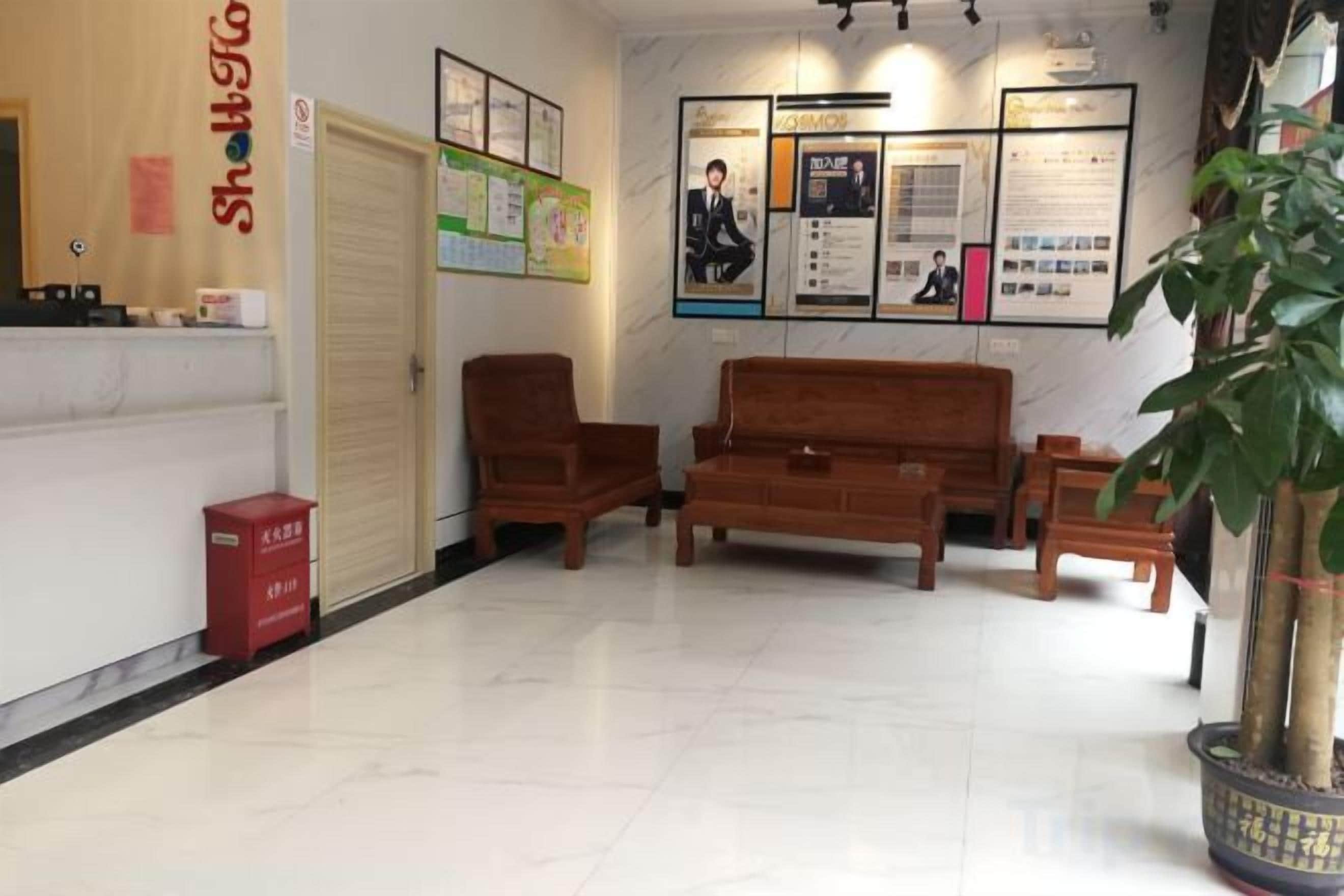A reception area with a reception desk, wooden seating, a potted plant, and informational posters on the wall.