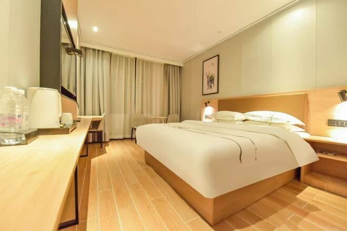 A hotel room with a bed, bedside table, and a desk with a chair.