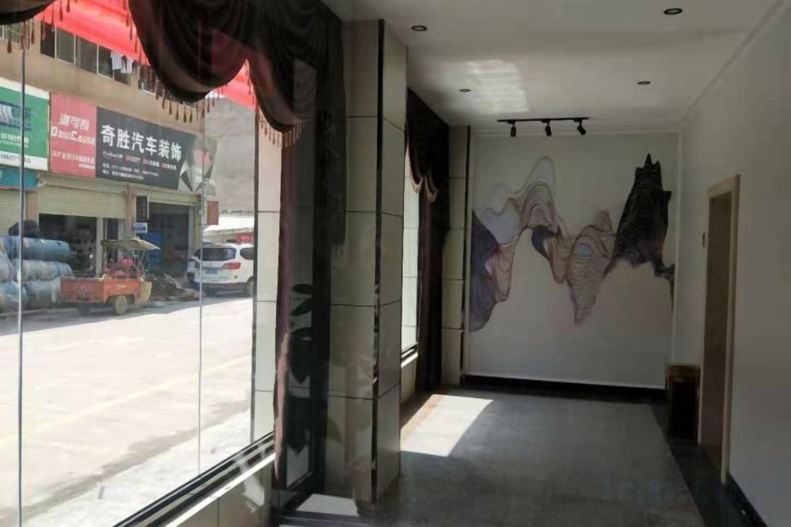 A hallway with a glass wall, a mural, and a door on the right.