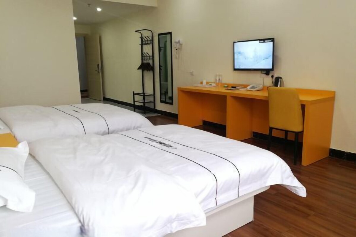 Una camera d'hotel con un letto matrimoniale, una scrivania con sedia, una televisione e uno specchio.