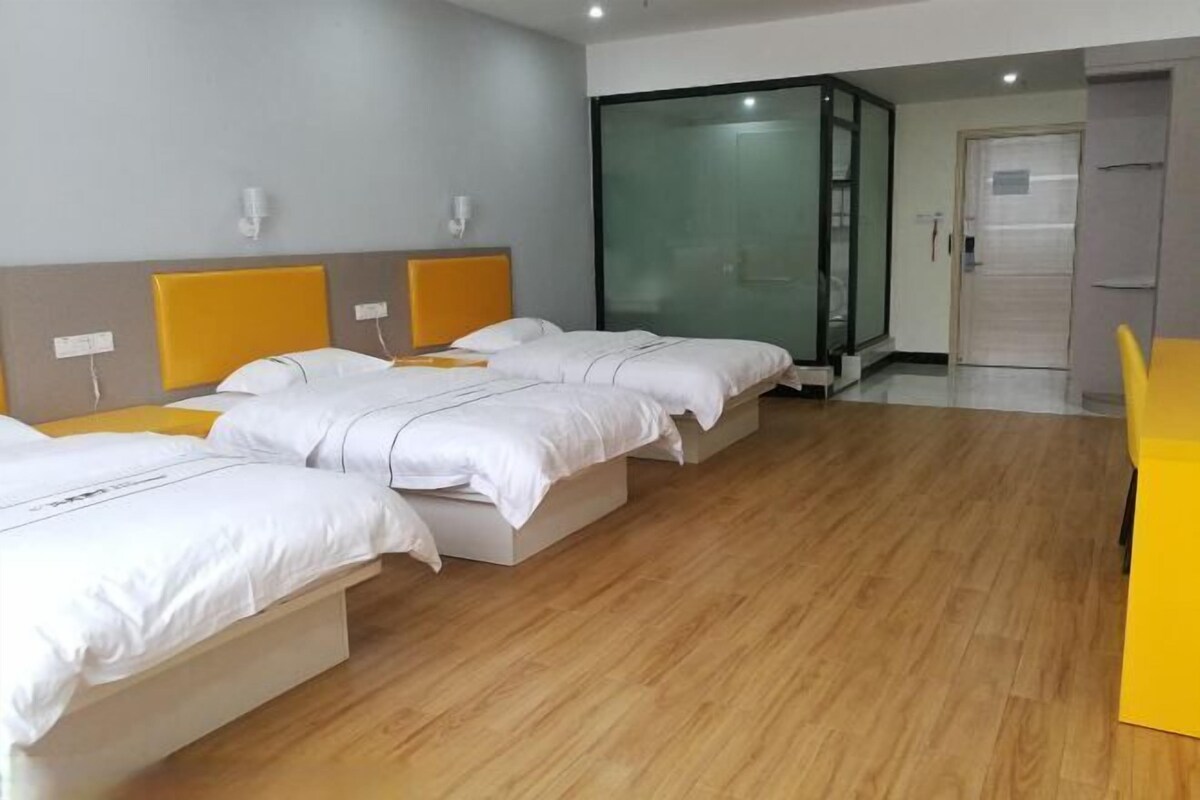 Camera d'albergo con tre letti, una porta scorrevole in vetro e un pavimento in legno.