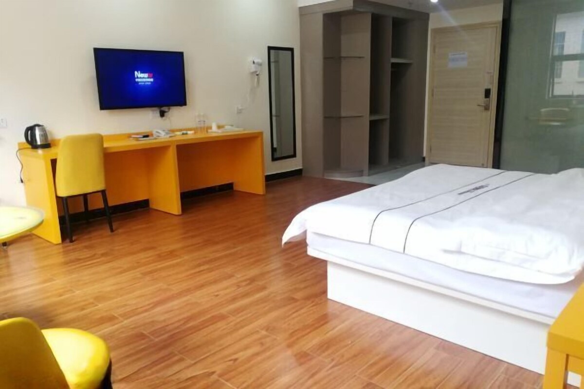 Una camera d'albergo con un letto, una scrivania, una sedia, una televisione e un armadio.